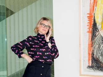 Television agent Janet Carol Norton stands in her Century City office wearing a patterned purple sweater and black skirt.