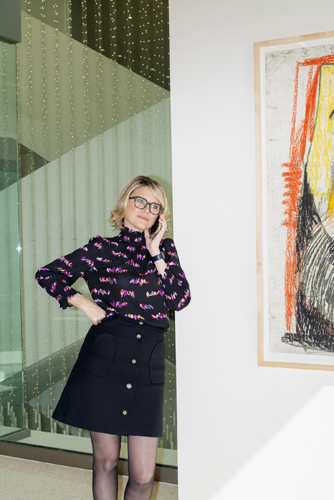 Television agent Janet Carol Norton stands in her Century City office wearing a patterned purple sweater and black skirt.