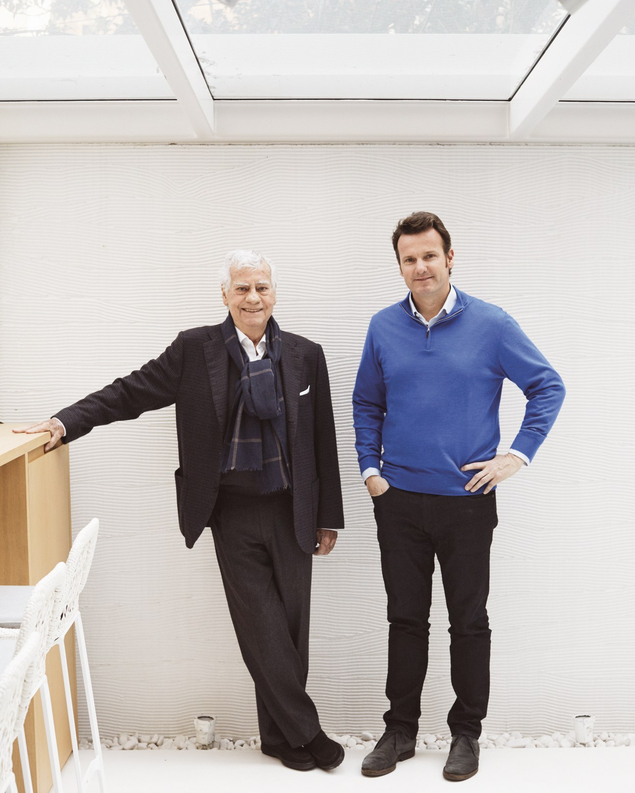 Manuel and Alex Alorda stand together in a bright, minimalist interior space.