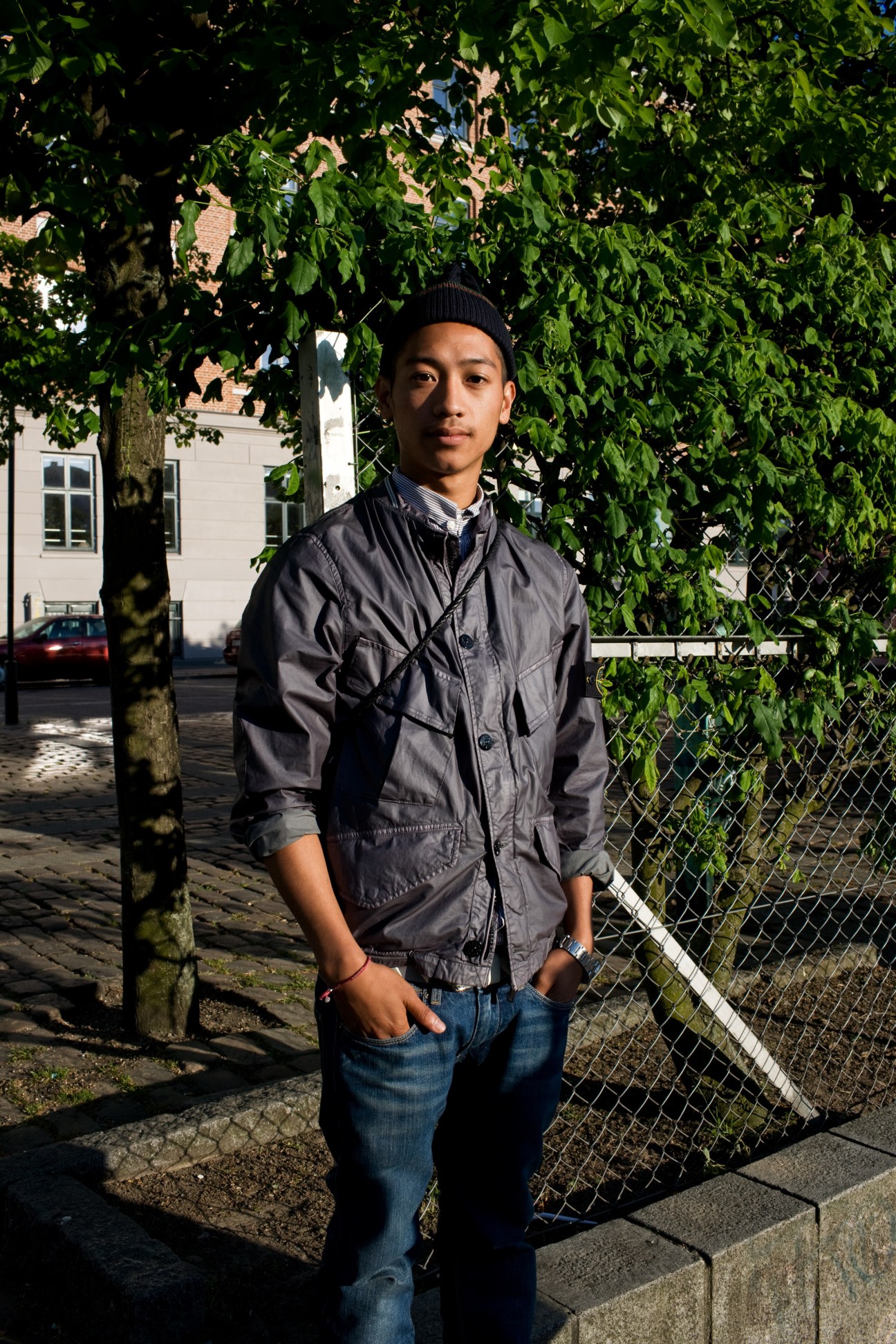 Young man standing under ivy-covered tree on Copenhagen street