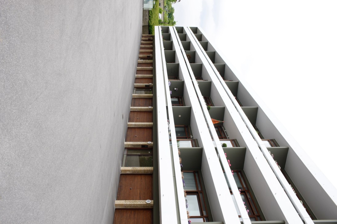 Modern residential building facade with white geometric framework and brown brick detailing in Klampenborg, Copenhagen.