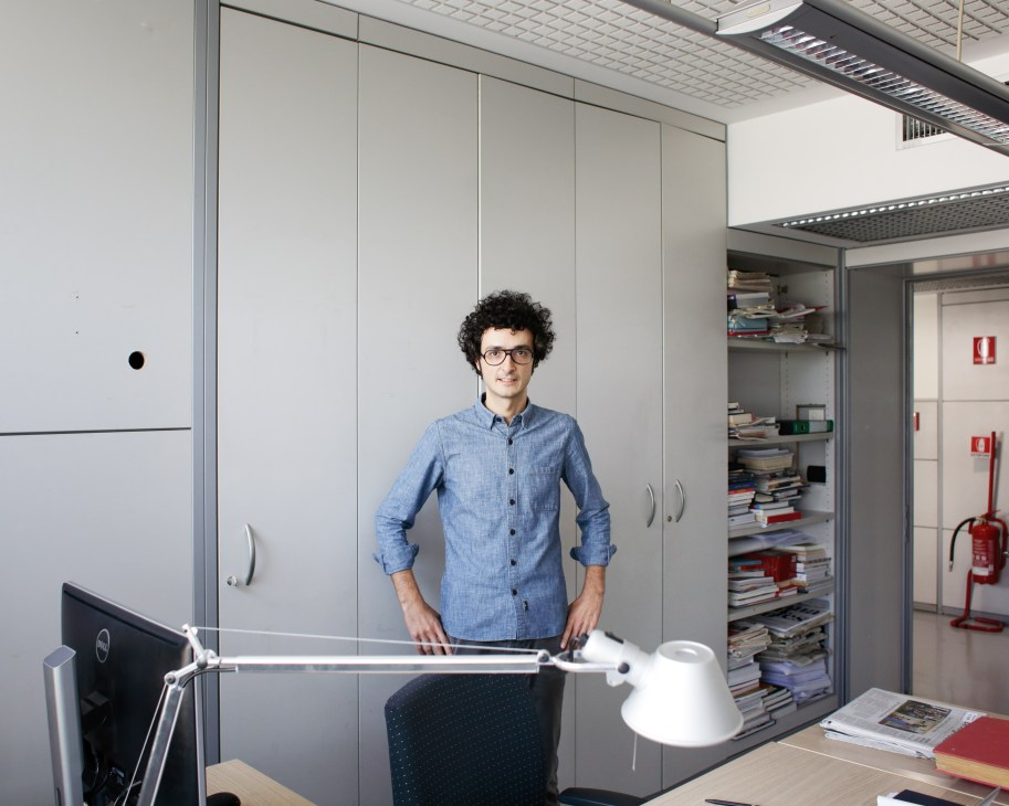 Designer Francesco Franchi standing in his modern office with shelves of publications behind him.