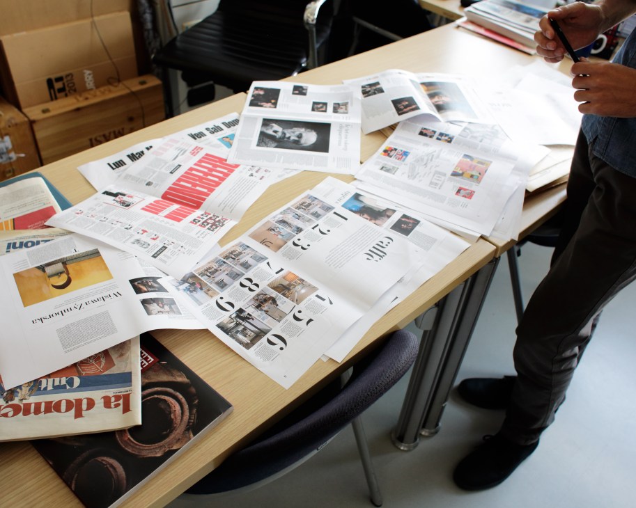 Work table displaying newspaper layout mock-ups and design materials for Robinson insert.