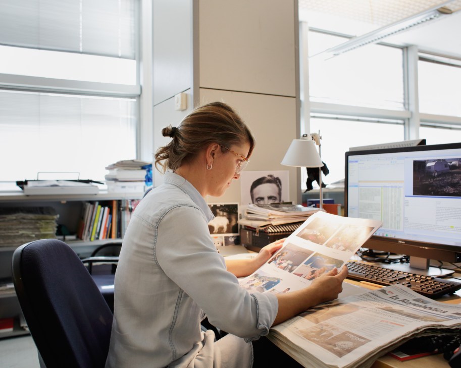 Photo editor Giulia Ticozzi examines newspaper clippings at her desk in La Repubblica's office.