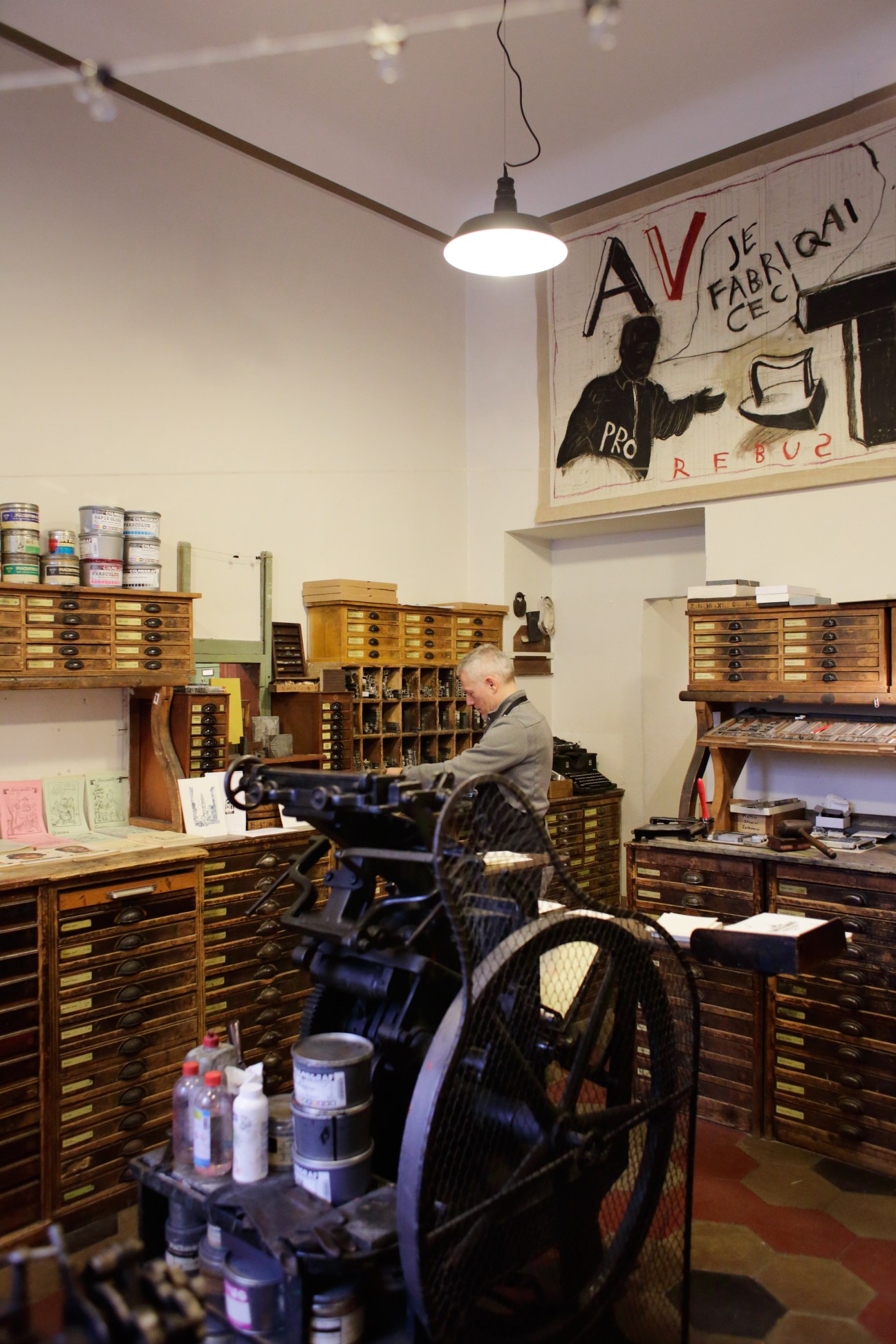 Staff member working at Fratelli Bonvini stationer shop surrounded by wooden storage drawers and vintage supplies.