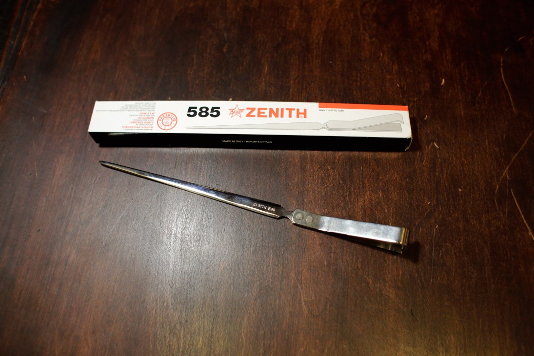 Vintage Zenith 585 letter opener with original packaging on dark wood surface.
