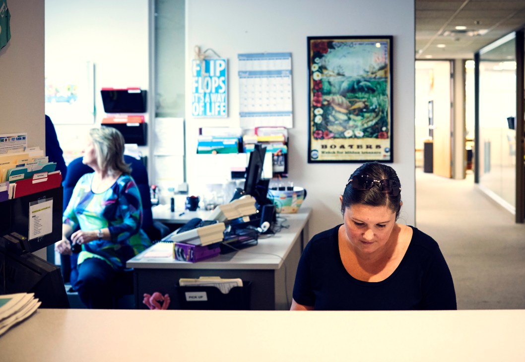 Reporter Kristin Swain taking notes at a desk in The Islander newspaper office.