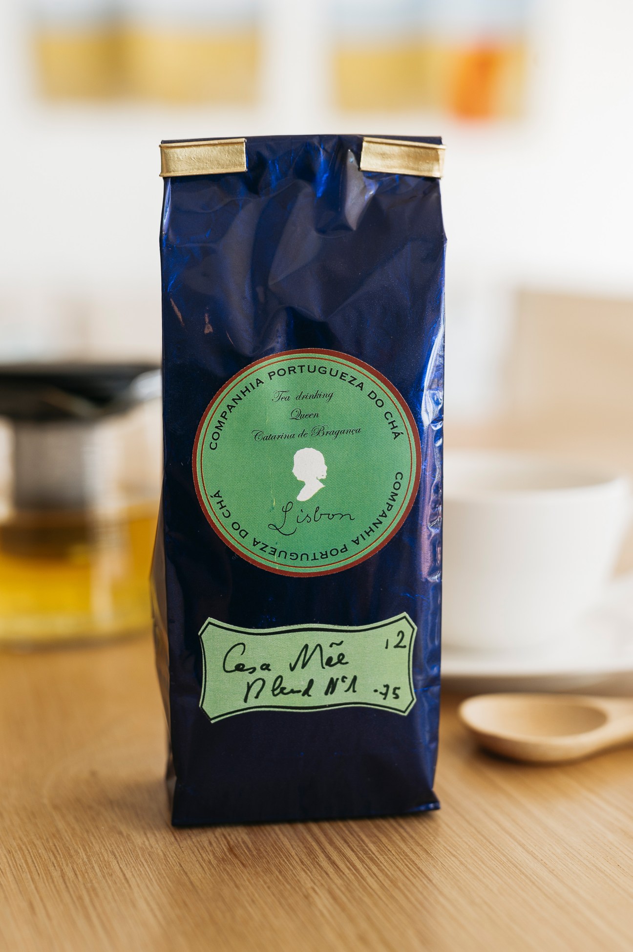 Hand-blended tea package for Casa Mãe hotel with custom green label and gold foil closure on wooden surface.