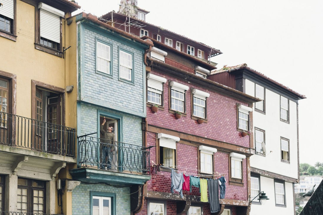 Multi-story Porto townhouses with colorful facades in yellow, blue and red brick showing signs of renovation and weathering.