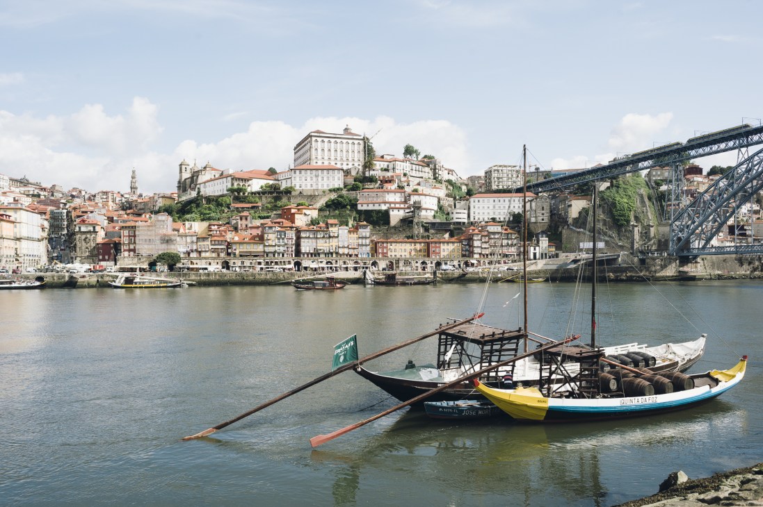 Porto's skyline with traditional rabelo boats on the River Douro and the Dom Luís Bridge visible on the right.