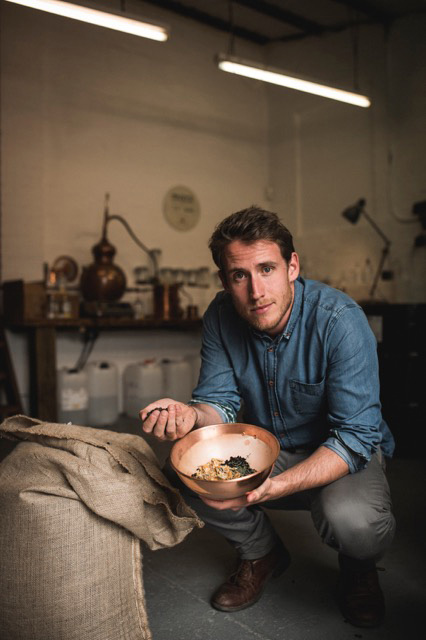 Rupert Holloway, founder of Conker Spirit gin distillery, holding a bowl of botanicals in his warehouse.