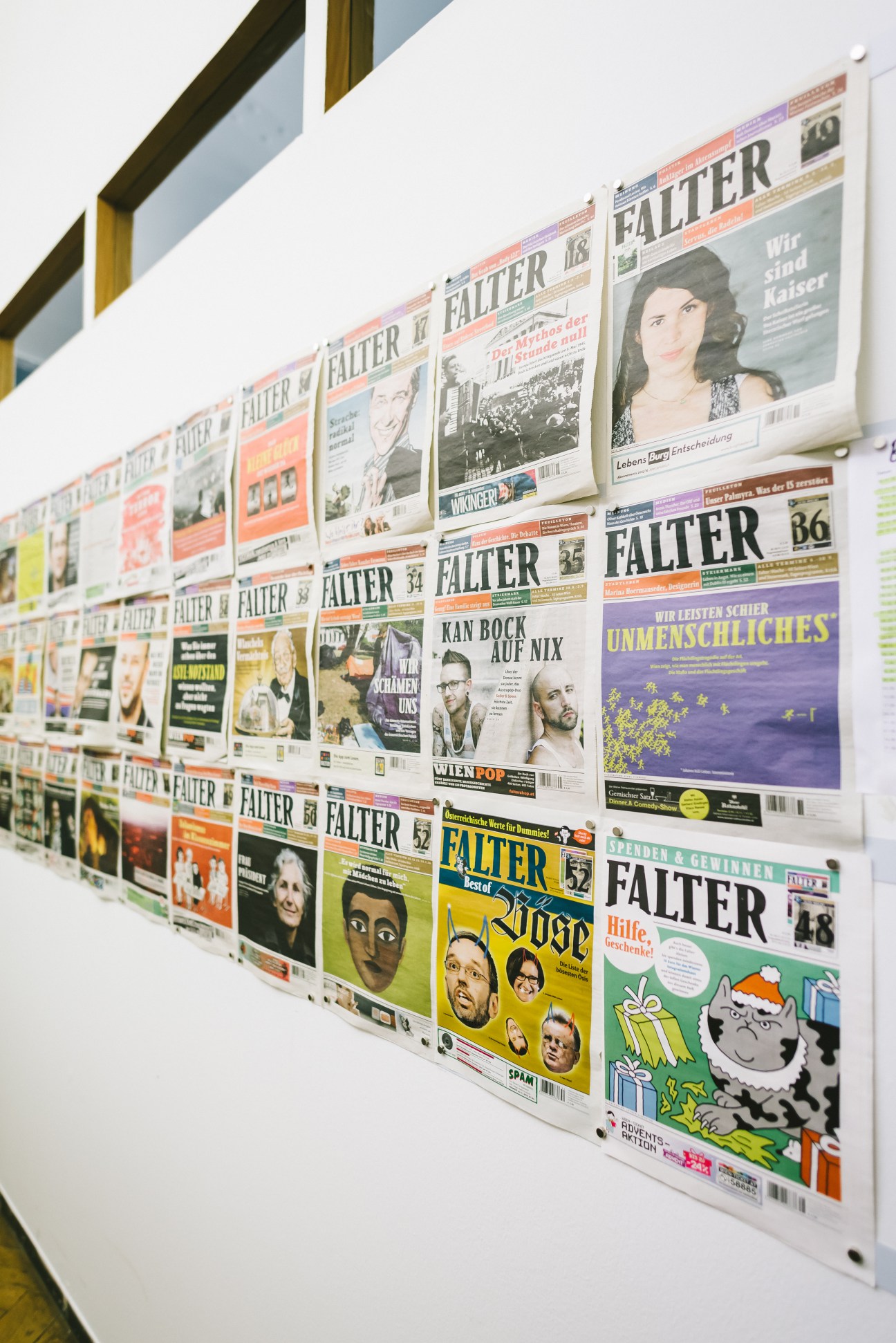 Falter magazine covers displayed on a white wall in the conference room, showing decades of issues with various designs and typography.