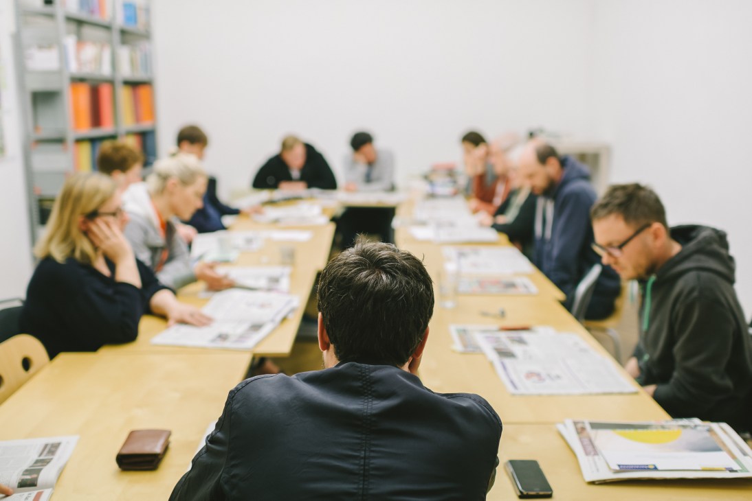 Falter magazine staff seated around a wooden conference table during an editorial review meeting.