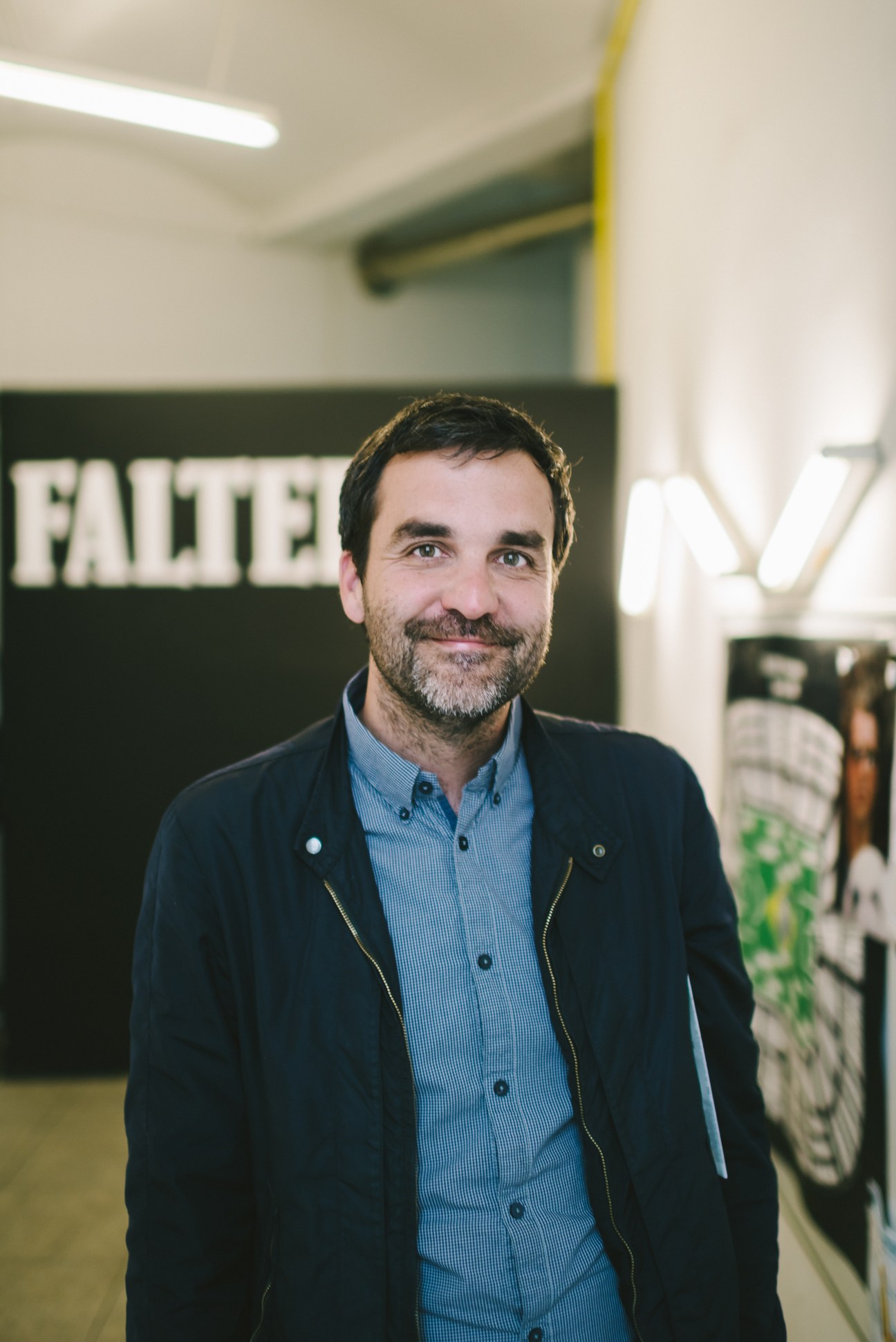 Florian Klenk, editor-in-chief of Falter magazine, stands in the Vienna office with the publication's logo visible behind him.