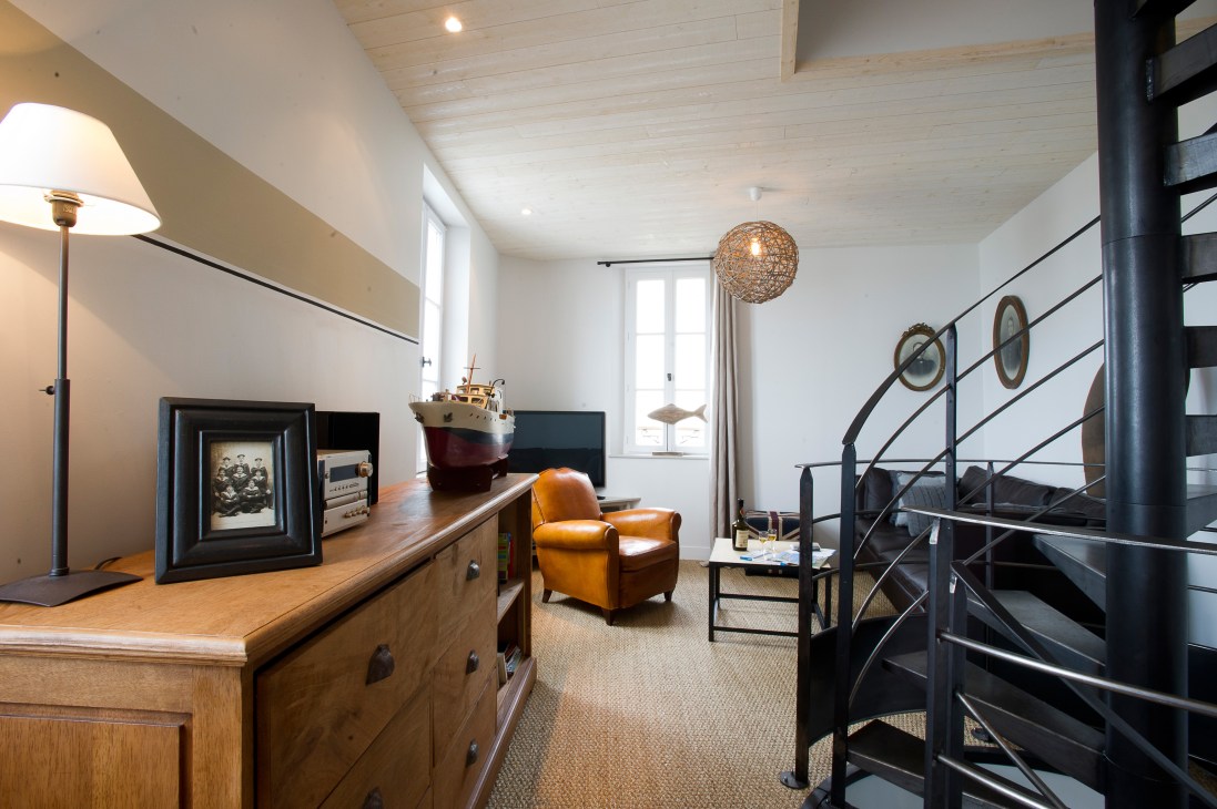 Modern hotel mezzanine level with wooden furniture, leather chair, spiral staircase and nautical decor.