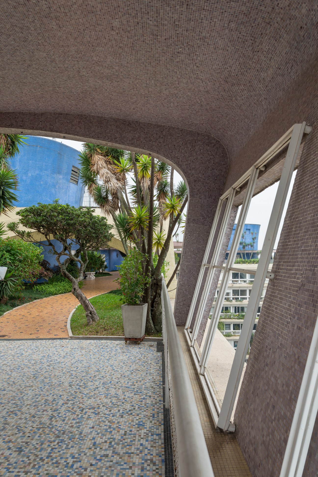 Covered rooftop area with blue mosaic tiles, curved brick ceiling, potted plants and view of internal courtyard.