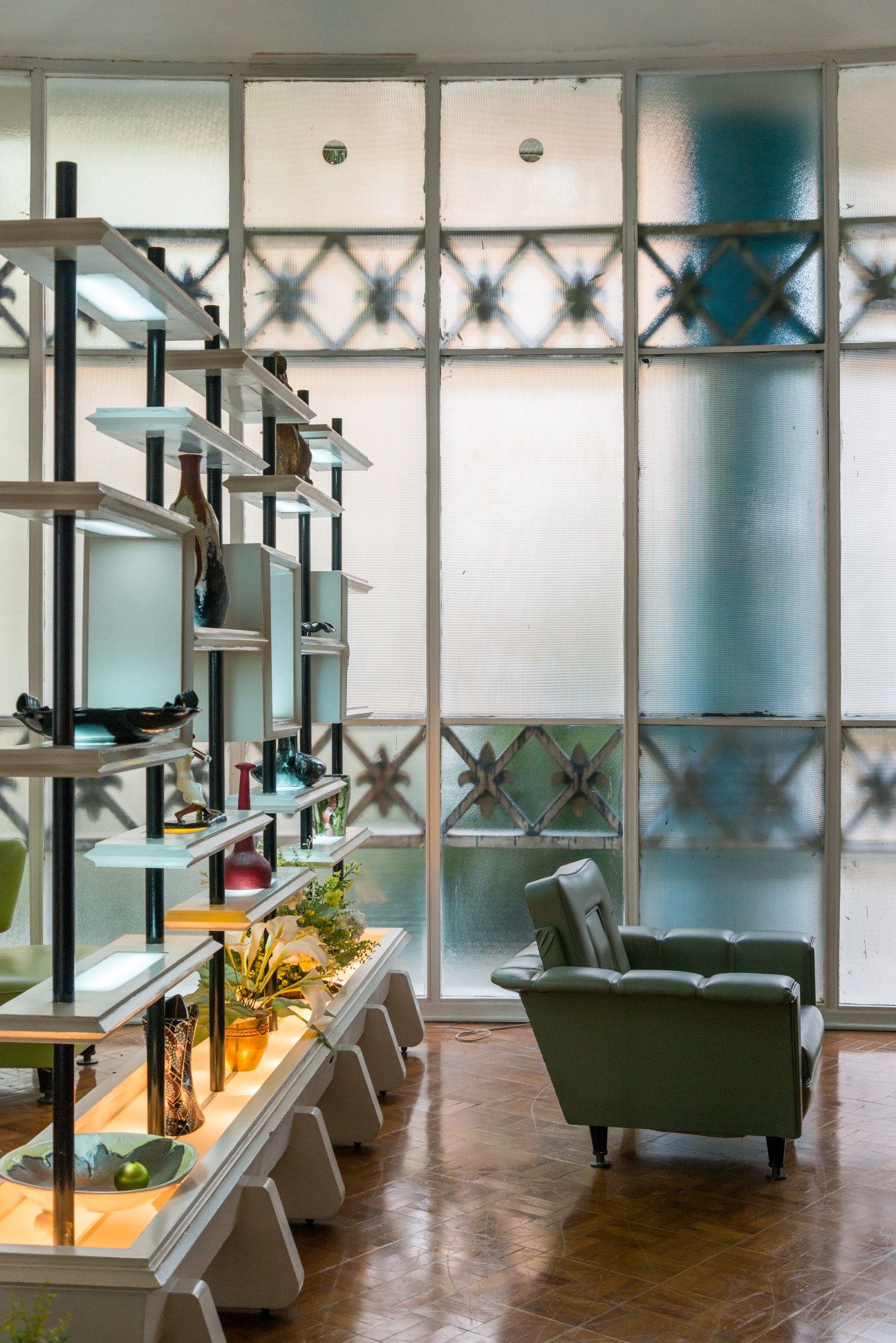 Communal party room in the Bretagne Building with modern shelving, green armchair, and large windows overlooking the courtyard.