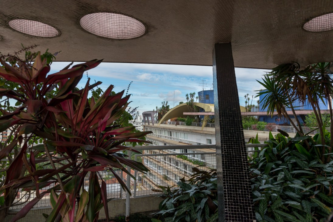 Rooftop terrace with red and green tropical plants overlooking the Bretagne Building's internal courtyard.