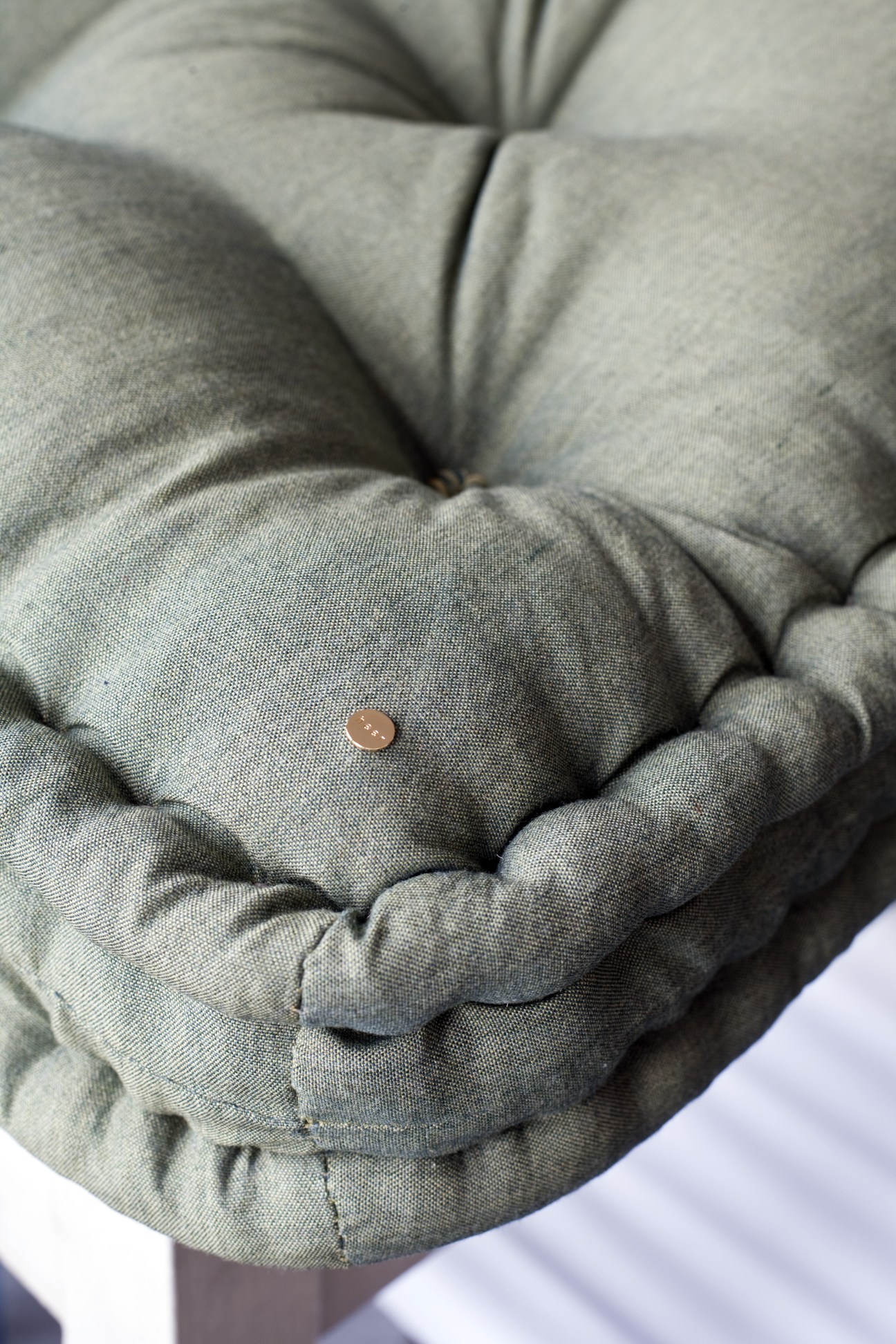 Close-up of a quilted grey fabric mattress with a penny for scale showing the craftsmanship detail