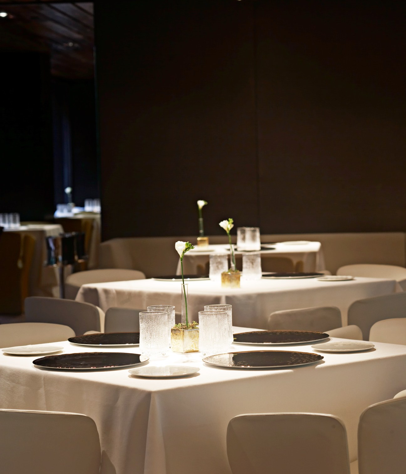Elegant dining room table set with white linens, black plates, and minimalist floral centerpieces at Mandarin Oriental Barcelona.