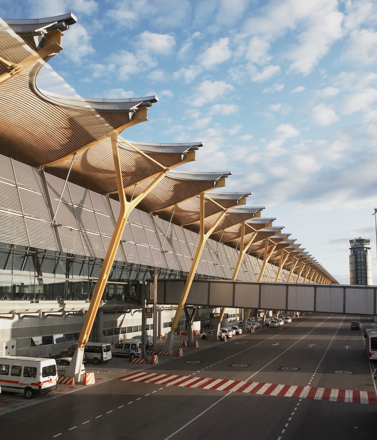 Richard Rogers's modern Barajas airport terminal with distinctive curved roof structure and golden supports.