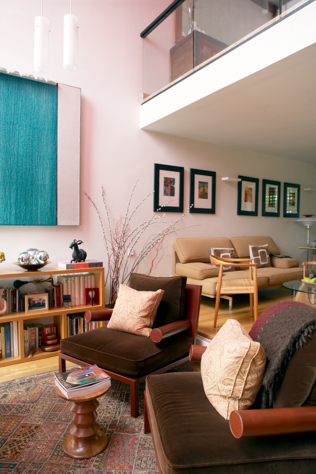Modern living room with pink walls, mid-century furniture, and turquoise artwork in Madrid's Parque Conde de Orgaz neighbourhood