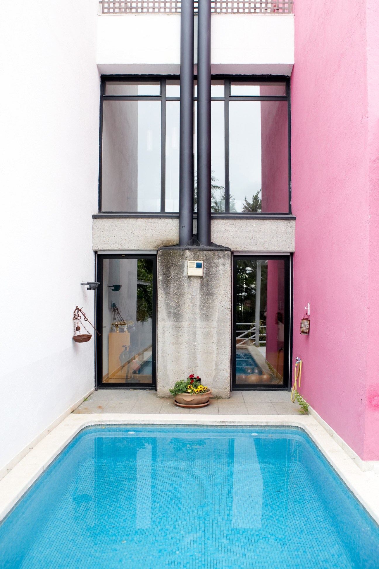 Modernist apartment courtyard with blue pool, pink walls, and black-framed windows