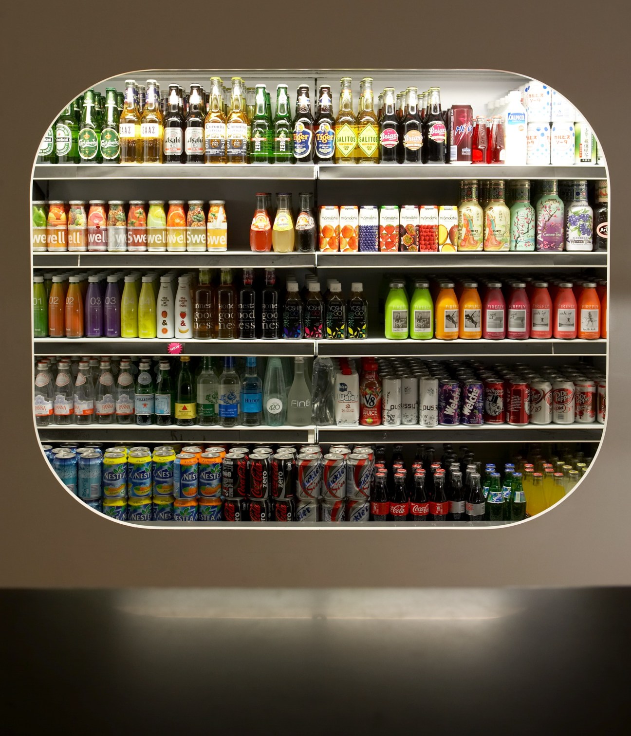 Refrigerated display case stocked with bottles of beer, soft drinks, juices and beverages at Isolée deli.