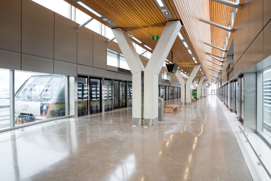 UP Express train platform at Toronto Pearson airport with wooden ceiling beams, Y-columns, and terrazzo flooring.