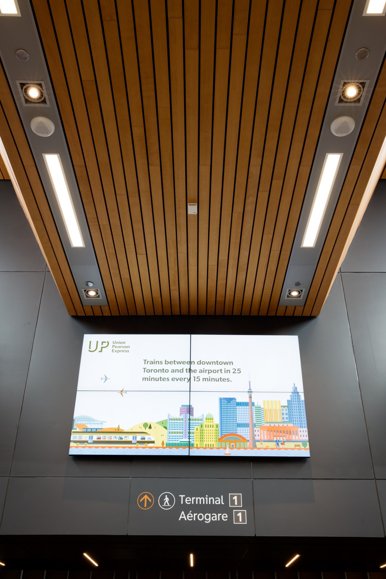 UP Express station signage with wooden ceiling and information screen about train service between Toronto and airport.