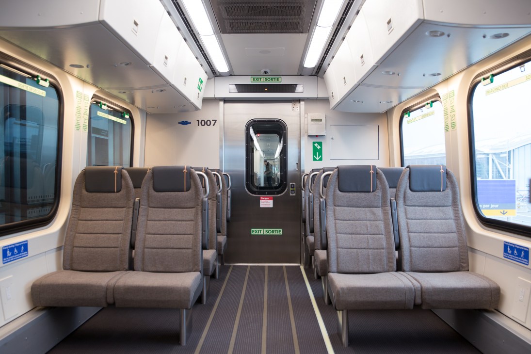 Interior of UP Express train carriage with grey upholstered seats and warm-toned ceiling panels.