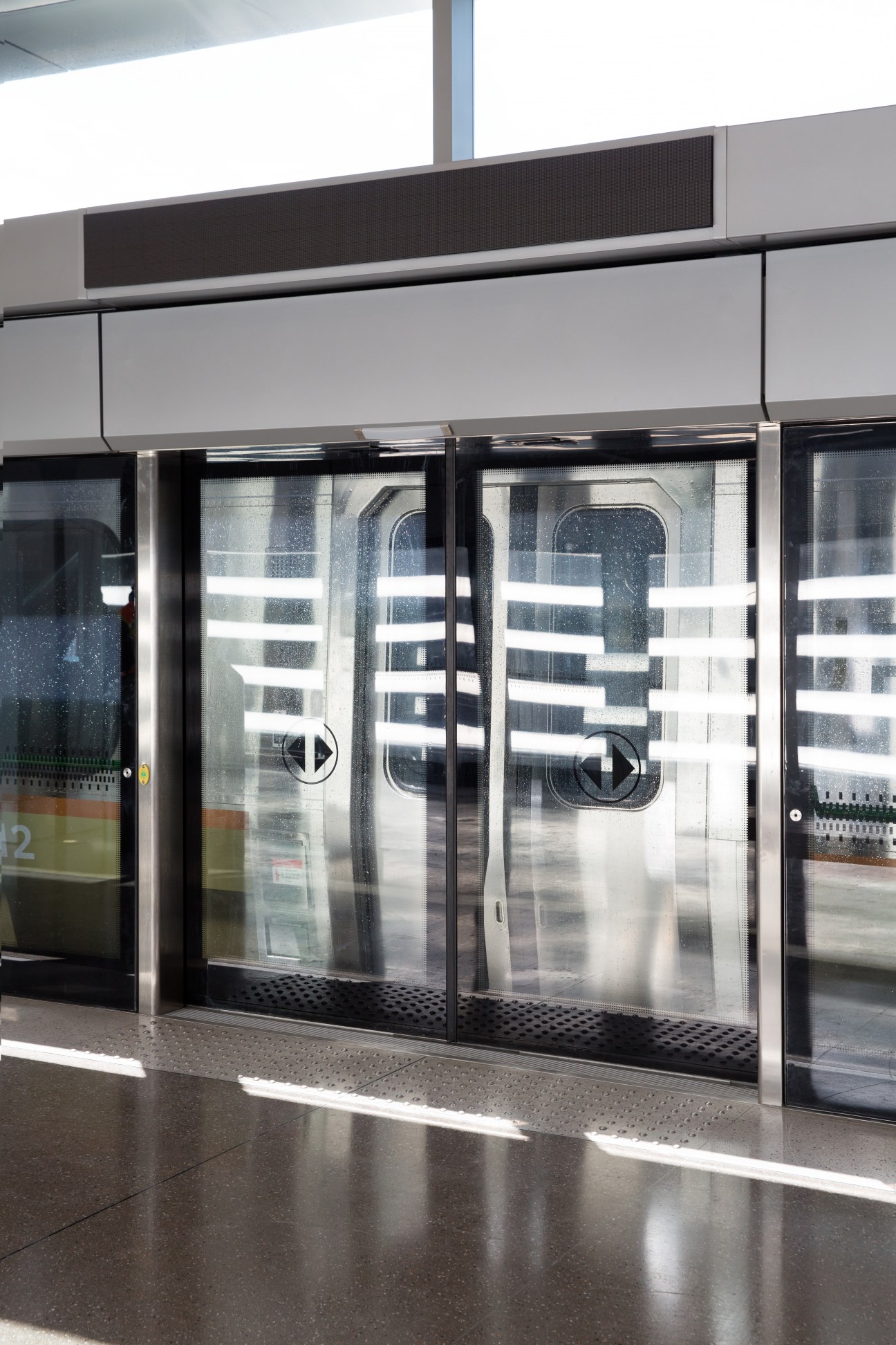 Automated glass doors with horizontal white striping at UP Express station.