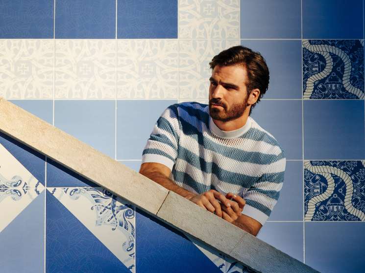 Man wearing Prada jumper and Frescobol Carioca t-shirt on blue and white tiled staircase in Lisbon.