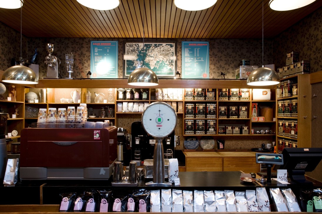 Fuglen café's vintage coffee bar featuring original 1960s counter, shelves, brass lamps, and Nordic design objects for sale.