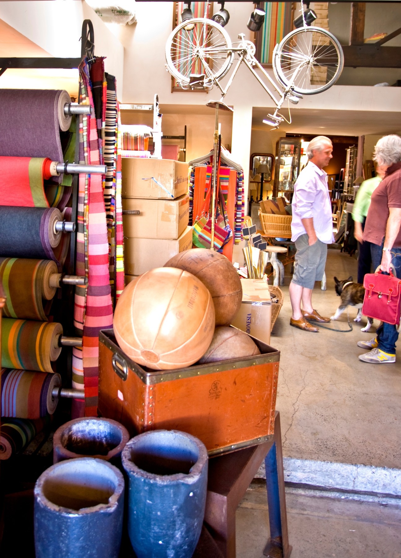 Interior of a Sydney shop displaying colorful ribbons on rolls, bicycles, basketballs, and vintage sporting goods with customers browsing.