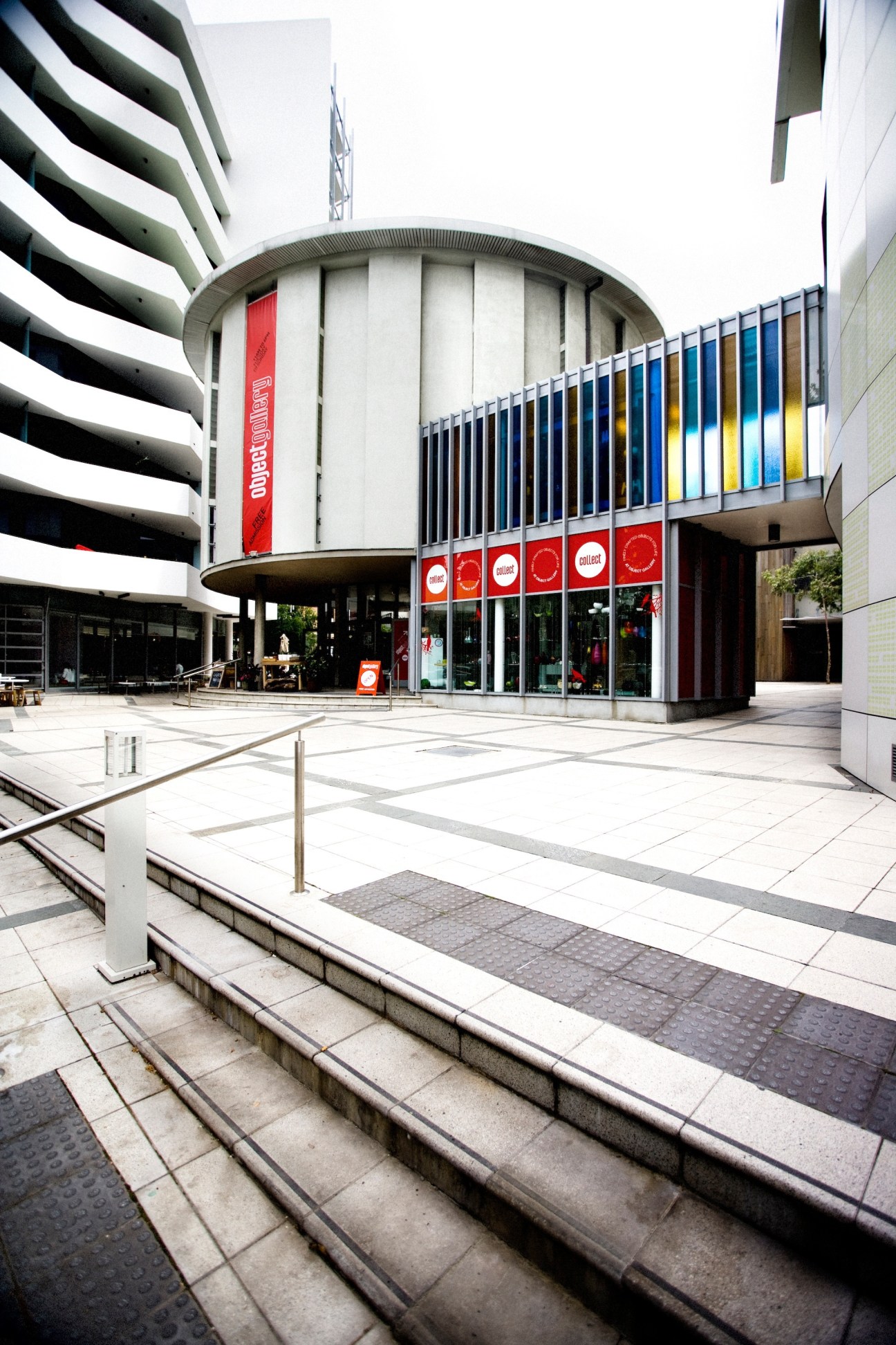 Exterior of Object gallery in a cylindrical modernist building with red signage and blue-yellow window panels.