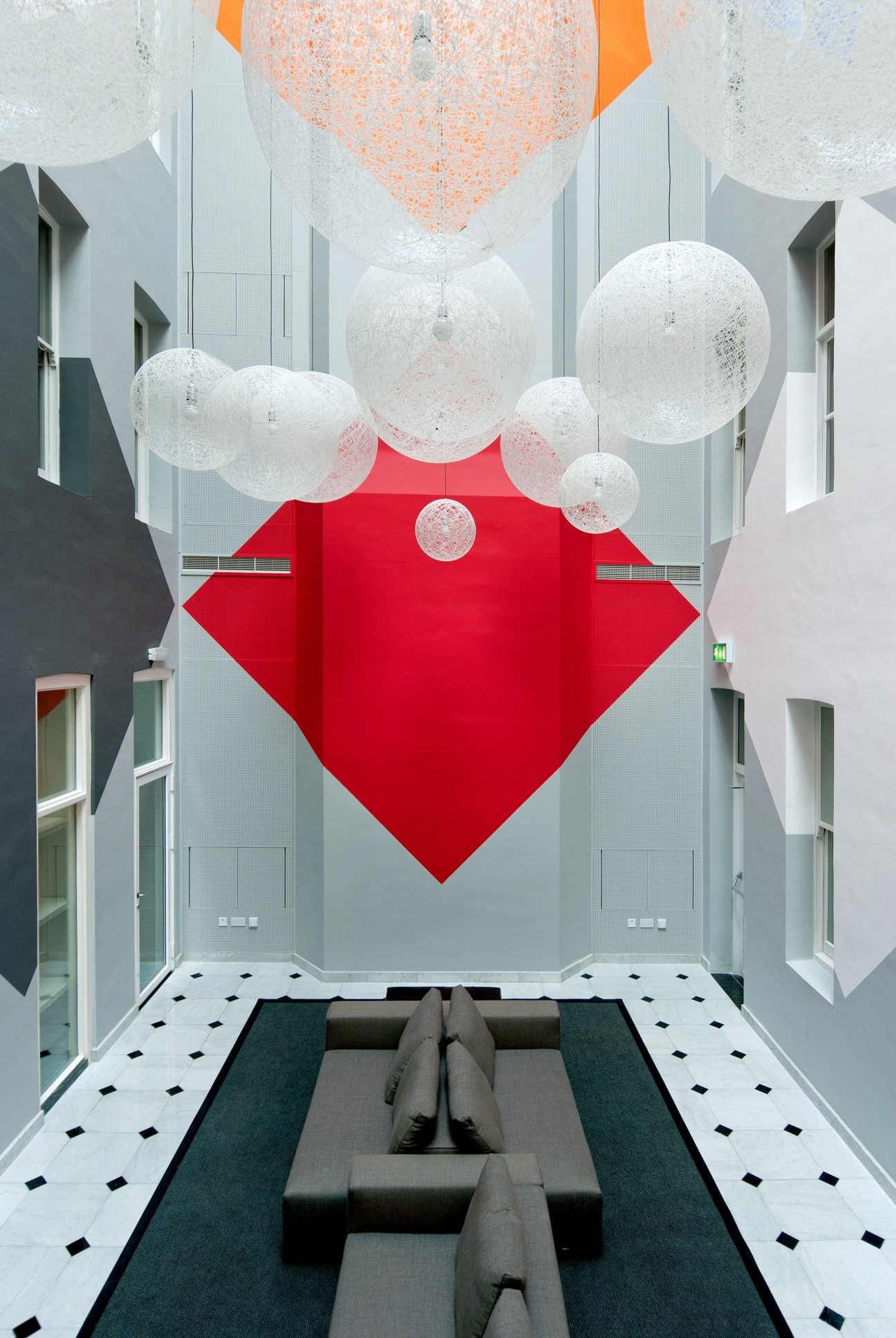 Dutch Embassy London interior with bold red diamond installation and hanging white spheres.