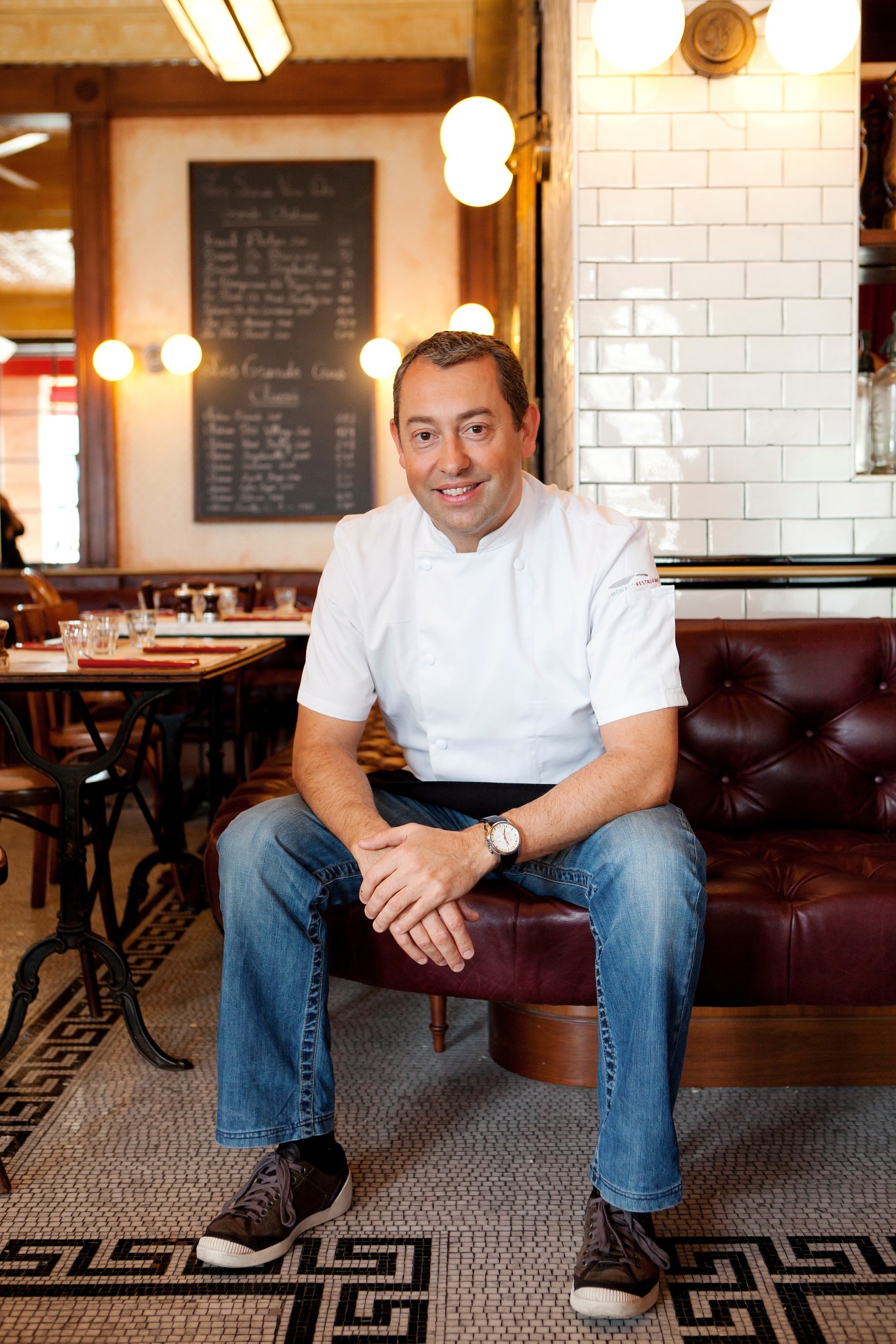 Executive chef Thierry Paludetto sits in Bouchon restaurant wearing a white chef's jacket.