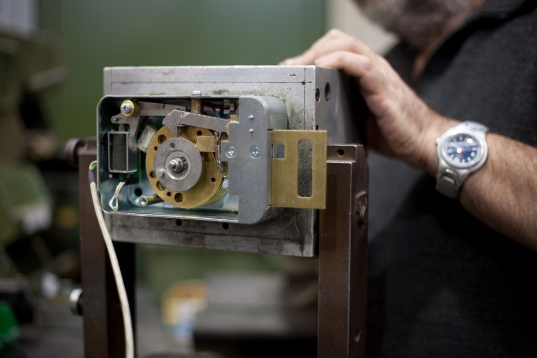 Close-up of Parma Antonio & Figli's mechanical combination lock showing brass and steel components being held by a technician.
