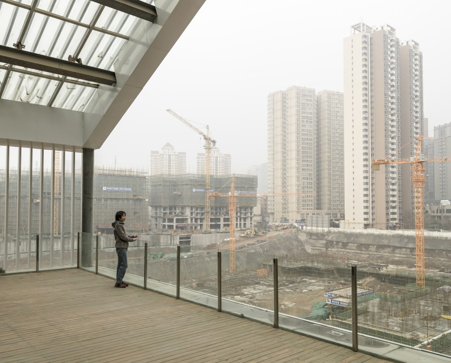 Person standing on a modern balcony overlooking construction cranes and residential towers in Xi'an's Hi-Tech Development Zone