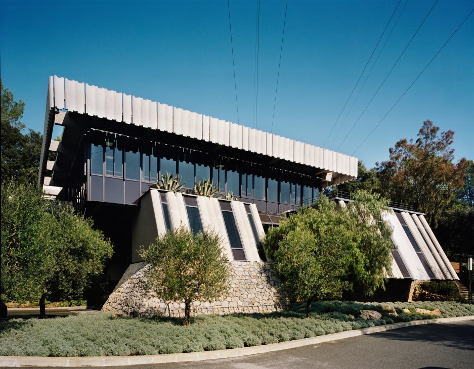 Modern building with white roof panels and black facade among green landscaping at Institut National de la Propriété.