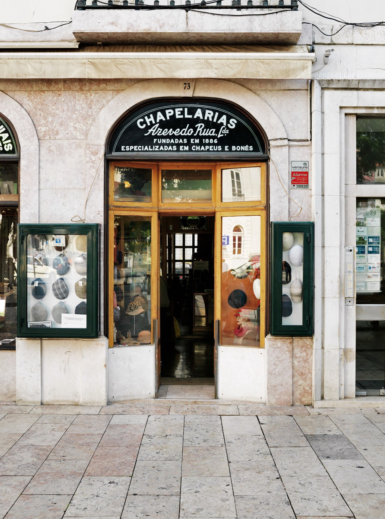 Exterior of Chapelaria Azevedo Rua, a historic hat shop in Lisbon with wooden-framed windows and green display cases.