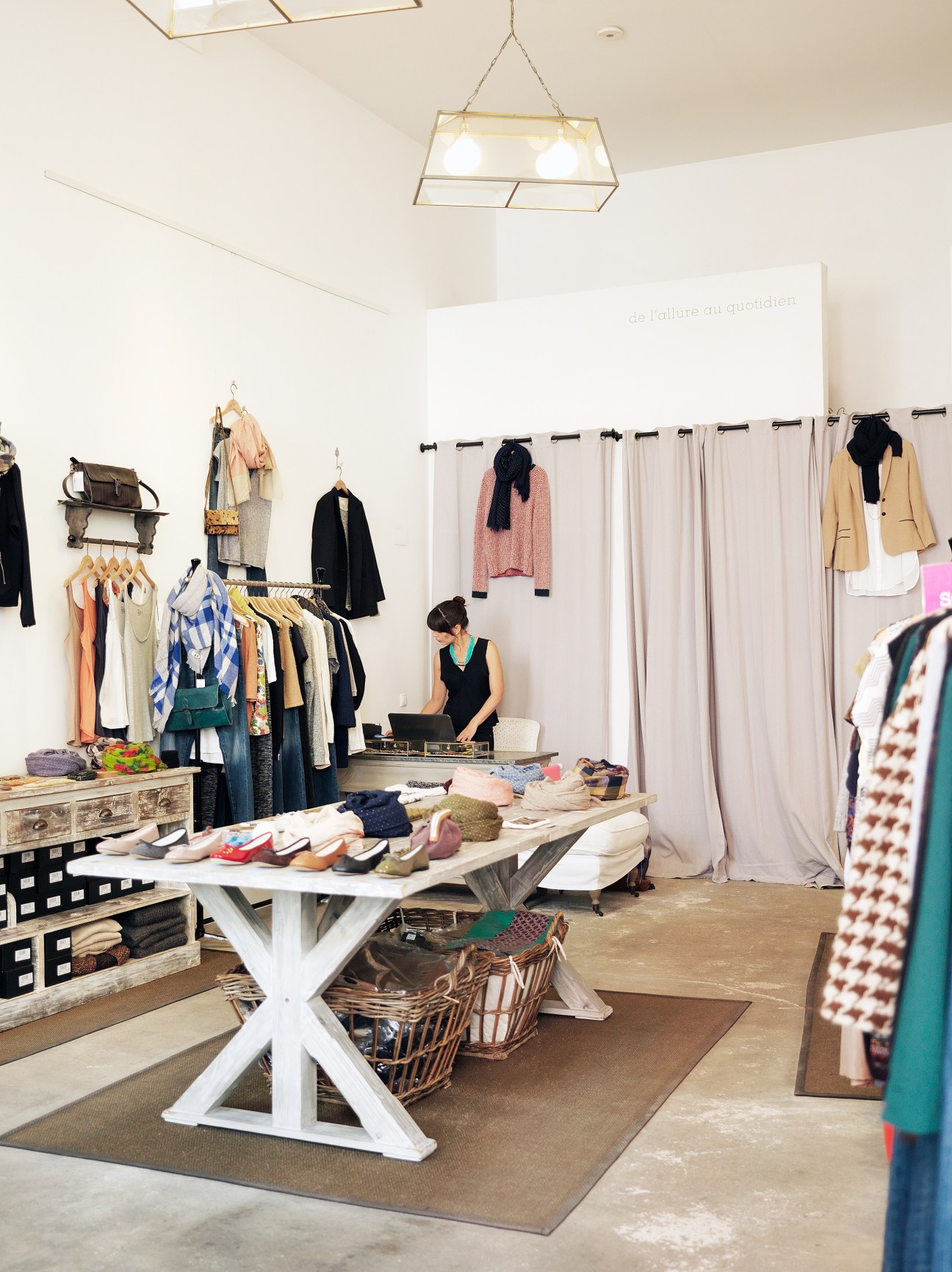 D'ici de et là womenswear boutique interior with clothing displays and shopkeeper at counter.