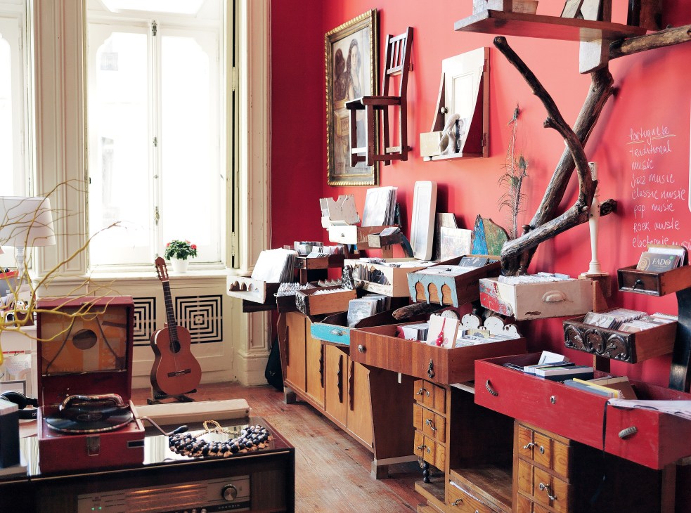 VLA Records shop interior with coral pink walls, wooden furniture, vinyl records, guitars, and decorative items.
