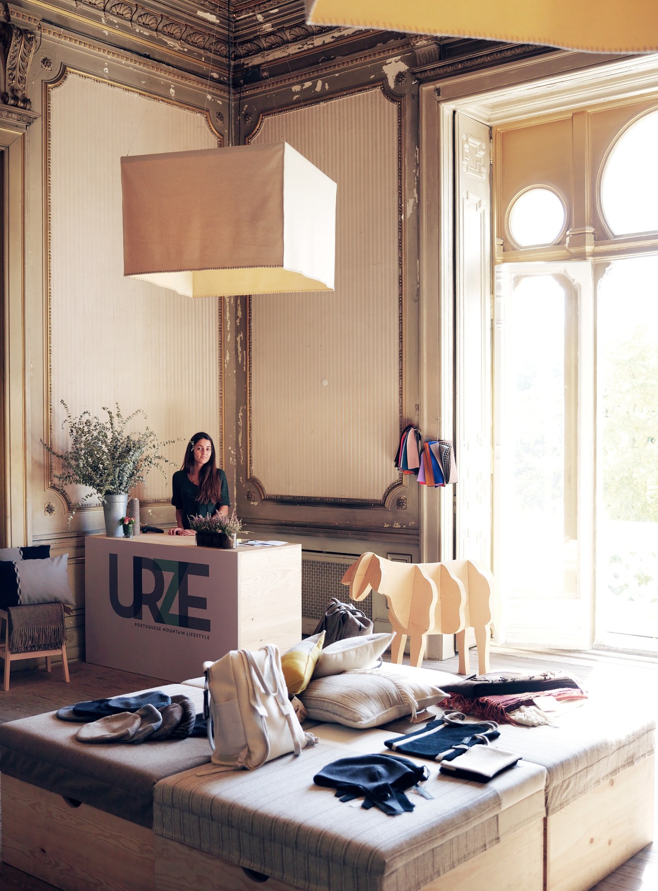Interior of Urze wool shop in Embaixada mall with staff member at desk and folded textiles displayed.