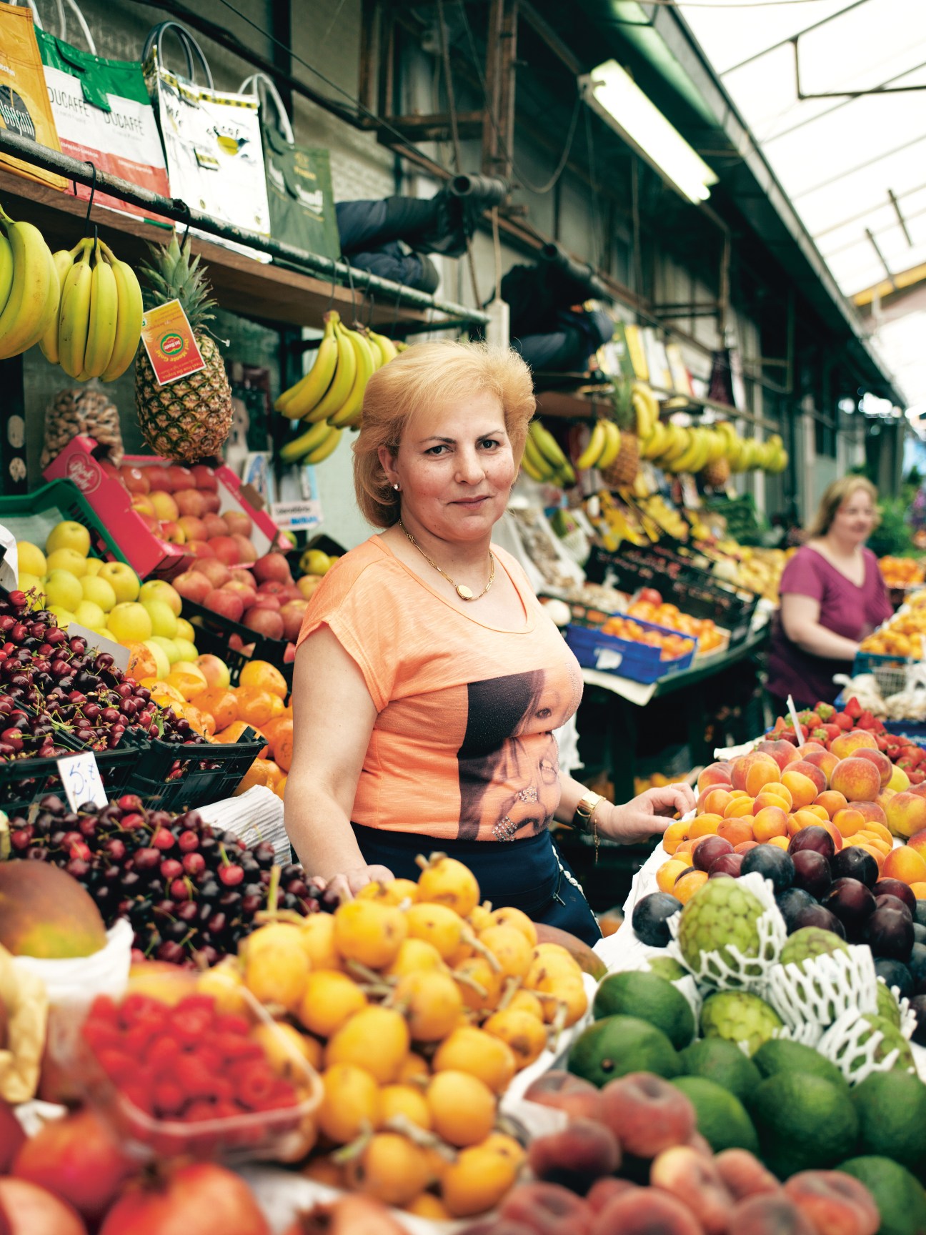 Fruit stallholder Ermelinda Monteiro at her stall in Mercado do Bolhão market surrounded by colorful fresh produce.