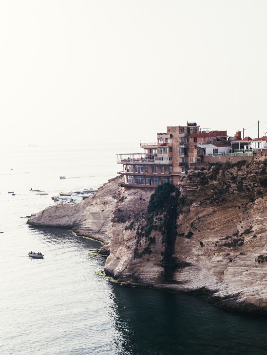 Colorful residential and restaurant buildings perched on rocky cliffs overlooking the Mediterranean Sea in Beirut.