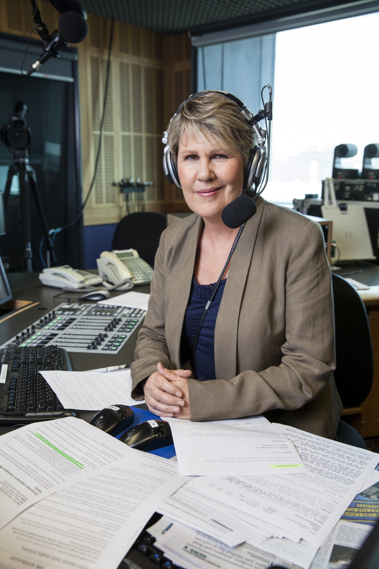 Fran Kelly, host of ABC Radio National's Breakfast programme, seated at her broadcasting desk wearing headphones and a beige blazer.