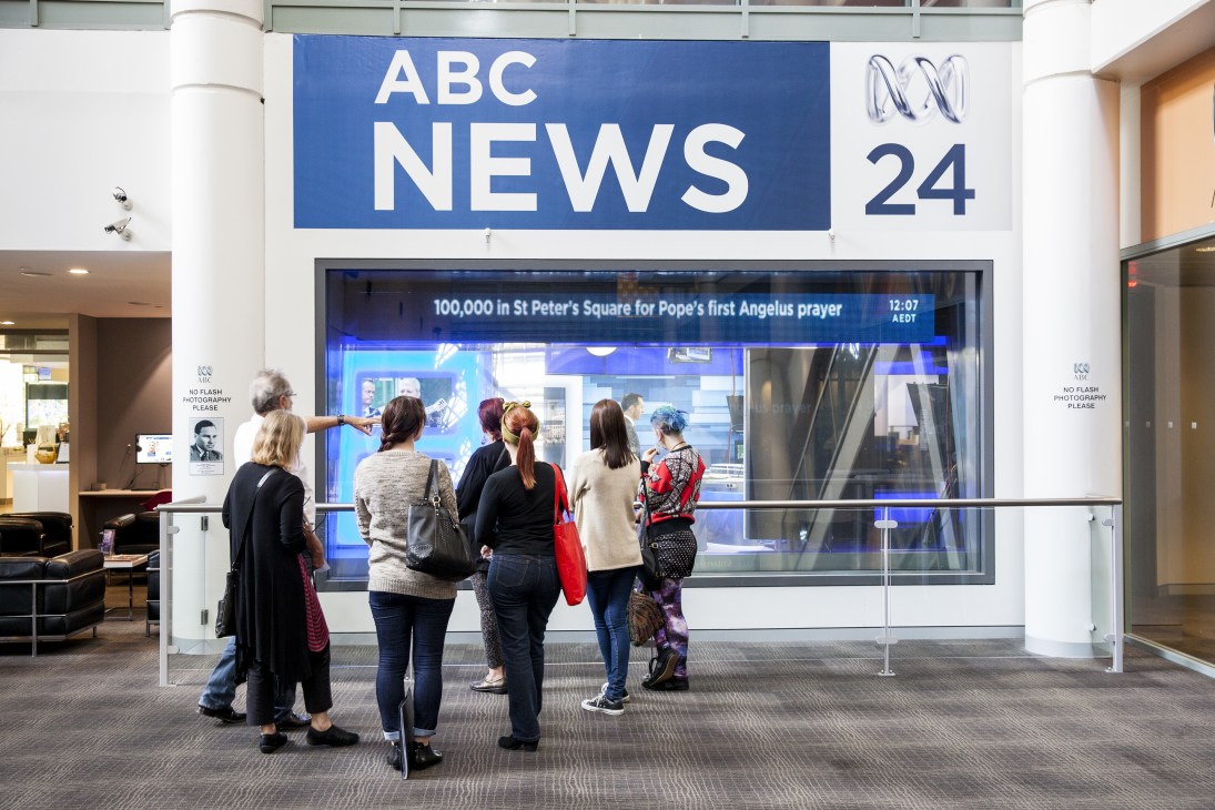 Visitors stand outside ABC News 24 studio with signage visible above large glass windows.