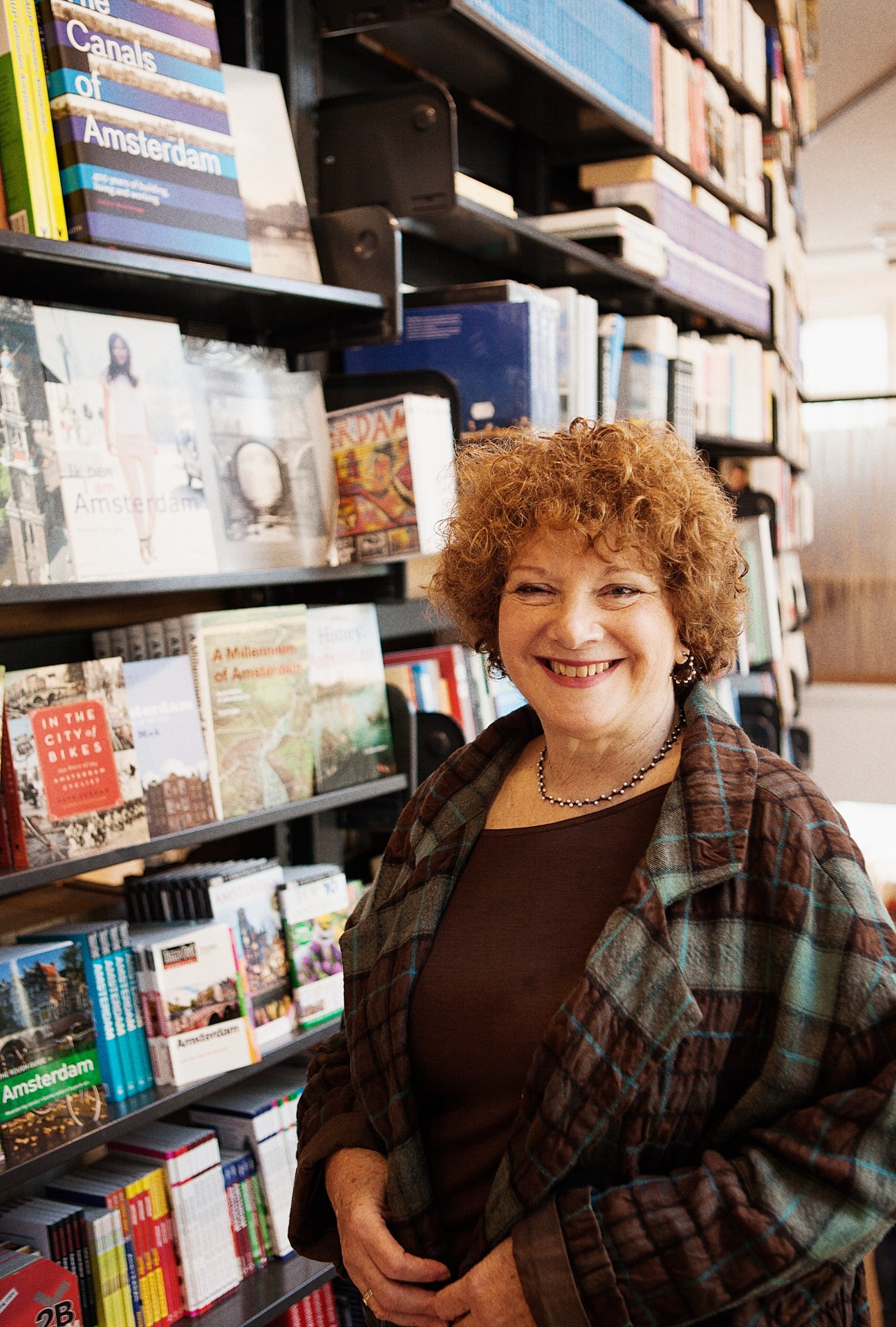 Lynn Kaplanian smiles at The American Book Center among shelves of books in Amsterdam.